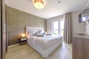 a bedroom with a white bed and a window at Strandliebe - 5 Sterne Ferienwohnung - Urlaub zwischen Ostsee und Bodden in Wustrow