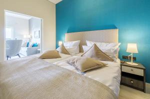 a large bed in a bedroom with a blue wall at Francis Drake Suite - 5-Sterne Wellnessurlaub mit Ostseeblick in Wustrow
