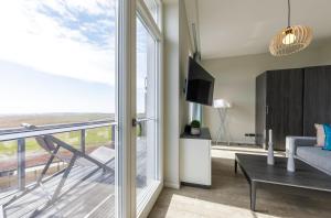 a living room with a couch and a tv and a balcony at Ostsee-Schönheit Wustrower Welle-Modernes 2-Zimmer-Apartment mit Panoramablick in Wustrow