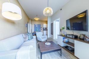 a living room with a white couch and a table at Kleine Welle - Haustierfreundliches Zwei-Zimmer Apartment mit Südbalkon und Platz für drei Personen im ersten Obergeschoss in Wustrow