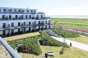 un edificio bianco con una collina erbosa vicino all'oceano di Ostseefeeling - 5 Sterne Ferienwohnung mit Südbalkon in der Seefahrtschule Wustrow a Wustrow