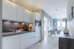 a kitchen with white cabinets and a dining room at Sommerbrise - 5 Sterne Ferienwohnung für die ganze Familie im Ostseebad Wustrow in Wustrow