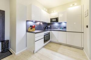 a kitchen with white cabinets and stainless steel appliances at Boddenzeit - Moderne Ferienwohnung mit Nordbalkon, Wellnessbereich und Nähe zum Ostseestrand in Wustrow