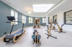 a gym with two treadmills and two exercise bikes at Boddenzeit - Moderne Ferienwohnung mit Nordbalkon, Wellnessbereich und Nähe zum Ostseestrand in Wustrow