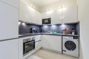 a kitchen with white cabinets and a washer and dryer at MEERGLÜCK - Unvergesslicher Urlaub in der ruhig gelegenen Ferienwohnung mit Blick auf die Ostsee in Wustrow