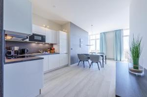 Una cocina con gabinetes blancos y una mesa y sillas. en Große Welle - Moderne 2,5-Zimmer Ferienwohnung mit Südbalkon und Boddenblick, en Wustrow