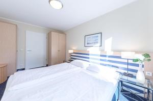a bedroom with a large white bed and two lamps at Bernsteinwind an der Seebrücke Zingst in Zingst