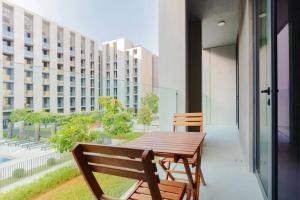 沙迦Sahab - Panoramic pool view 1BR Tiraz Building的大楼阳台上的一张木桌和椅子