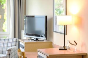 a hotel room with a tv and a desk with a lamp at Strandhafer an der Seebrücke in Zingst +12 photos