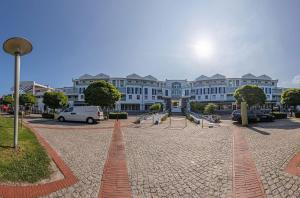 a large white building with cars parked in a parking lot at Grevenburg an der Seebrücke Zingst in Zingst +11 photos