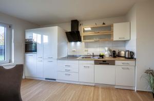 eine Küche mit weißen Schränken und einer Spüle in der Unterkunft Ferienhaus Casa Castagno mit Garten, Balkon und Sauna- heißt Sie herzlich willkommen! in Alt Schwerin