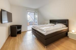 ein Schlafzimmer mit einem Bett und einem Stuhl und einem Fenster in der Unterkunft Ferienhaus Casa Castagno mit Garten, Balkon und Sauna- heißt Sie herzlich willkommen! in Alt Schwerin