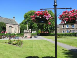 two hanging baskets of flowers on a pole in front of a building at Bankhouse B&B in Aberlour