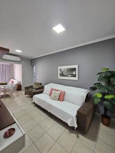 a living room with a couch and a palm tree at Flat Golden Beach Pitangueiras Apartamento in Guarujá