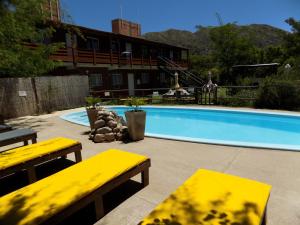 a swimming pool with yellow benches in front of a building at HoltFor in Potrero de los Funes