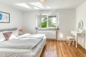 a white bedroom with a bed and a window at Ferienhaus Eddi am Tiefwarensee in Waren