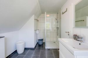 a white bathroom with a sink and a shower at Ferienhaus Eddi am Tiefwarensee in Waren +18 photos