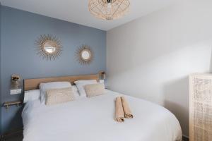 a bedroom with a white bed with two mirrors on the wall at Central appartement with terrace and free parking in Deauville