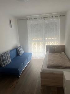 a living room with a blue couch and a window at Yasmin in Kressbronn am Bodensee