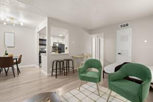 a living room with green chairs and a bedroom at Central & Cozy in Austin