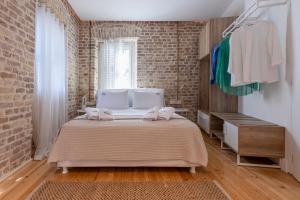 a bedroom with a bed and a brick wall at Vailato Swan White Suite in Corfu