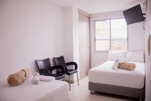 a bedroom with two beds and chairs and a window at Hotel Omaga El peñol- Guatape in El Peñol +30 photos