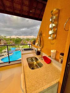 a kitchen with a sink and a view of a pool at Flats, Apartamentos e Bangalôs na Praia dos Carneiros, ao lado da Igrejinha de São Benedito in Praia dos Carneiros