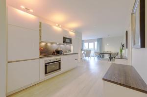 a kitchen with white cabinets and a dining room at Strandlounge - 5 Sterne-Wohnung mit XXL-Balkon, Wellness & Boddenblick in Wustrow