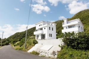 a white building on a hill next to a road at Kanasha Building A - Vacation STAY 49732v in Ōkachi