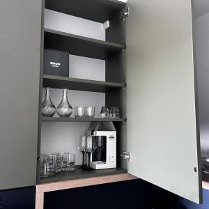 a cupboard with wine glasses and a coffee maker at WieloApartment Radom - Paderewskiego in Radom