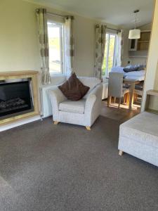 a living room with a chair and a fireplace at Rubys Retreat - 6 Berth Caravan in Newquay, Cornwall in Newquay +22 photos