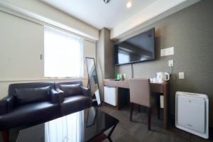 a hotel room with a desk and a couch and a television at Minakuchi Century Hotel - Vacation STAY 35331v in Koka +2 photos