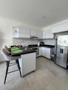 eine Küche mit weißen Schränken, einer Spüle und einem Kühlschrank in der Unterkunft Apartamento con hermosa vista y piscina en Santa Marta in Gaira