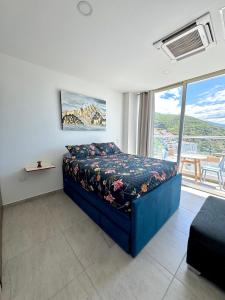 ein Schlafzimmer mit einem Bett und einem großen Fenster in der Unterkunft Apartamento con hermosa vista y piscina en Santa Marta in Gaira