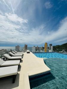 ein Swimmingpool mit Liegestühlen auf einem Gebäude in der Unterkunft Apartamento con hermosa vista y piscina en Santa Marta in Gaira