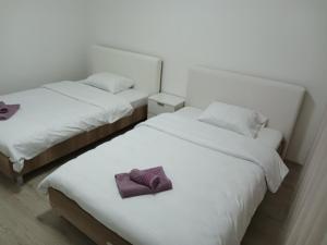 two beds with white sheets and a purple towel on them at Premium Square Apartment in Skopje