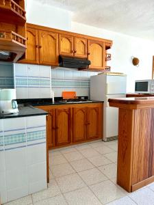 a kitchen with wooden cabinets and a white refrigerator at Mangos Mar E in Puerto Naos
