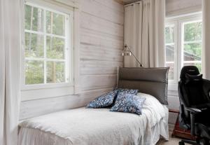 a bedroom with a bed with a chair and windows at Trekker's Haven: Noux National Park Retreat in Espoo