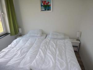 two beds in a bedroom with white sheets and pillows at Family-Friendly Holiday Home in Breskens +15 photos