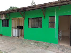 a green house with a dog in a cage at Kitnet bem localizada in Corumbá
