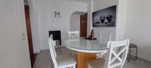 Un comedor con una mesa de cristal y sillas blancas. en Kattegat, en Puerto Madryn