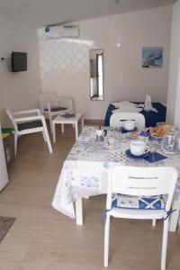 a dining room with a table and white chairs at Casa Vacanza da Sara in Custonaci
