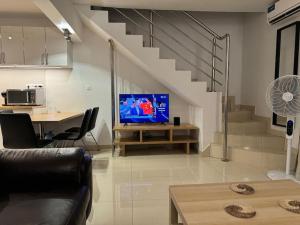a living room with a tv and a table and stairs at Villa à la Résidence Paradis 2 in Sali Poulang