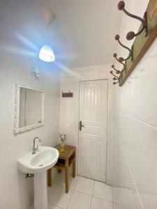a white bathroom with a sink and a mirror at Casa Dos Gringobz in Búzios