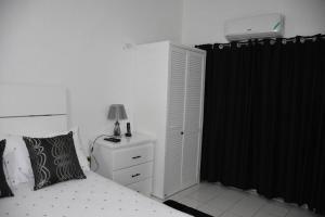 a bedroom with a white bed and a black curtain at White River Apartment 9, Great Pond- Ocho Rios in Stanmore Grove
