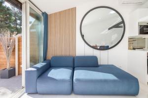 - un canapé bleu dans une chambre avec un miroir dans l'établissement Village Naturiste R4N - La Villa GreenWood, au Cap d'Agde