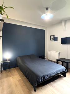 a bedroom with a bed and a blue wall at Résidence des Carmes in Dol-de-Bretagne