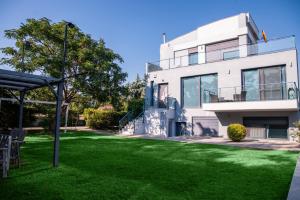 a white house with a green lawn in front of it at Villa Linda in Thessaloniki