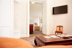a living room with a table and a tv on a wall at Exklusive Suiten im Schloss Horn in Horn
