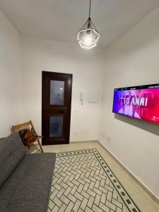 ein Wohnzimmer mit einer Couch und einem Fernseher an der Wand in der Unterkunft La Casetta in Trapani